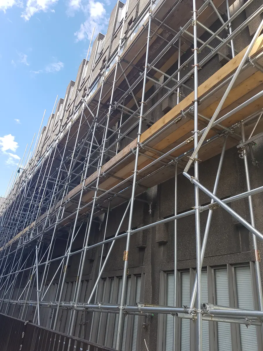 A long scaffold with boarded lifts along a commercial building