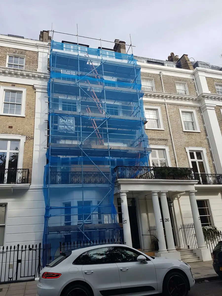 A townhouse scaffolded and wrapped in blue netting