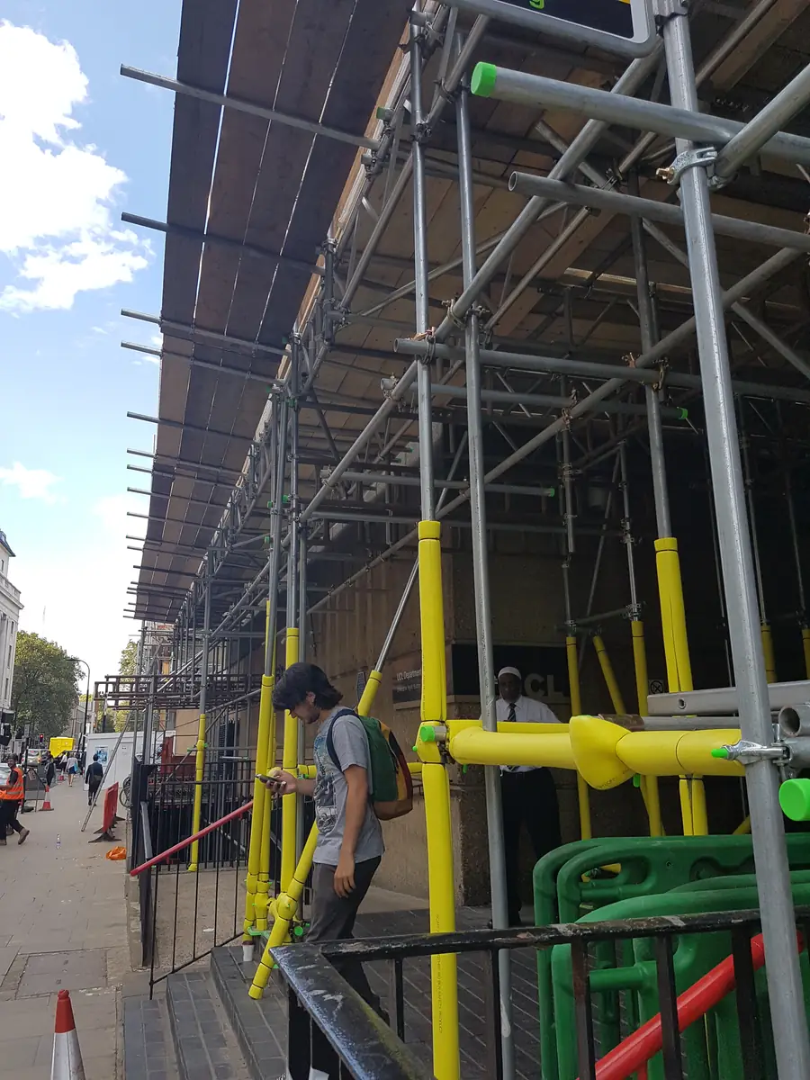 Scaffold over a pavement with a covered walkway underneath
